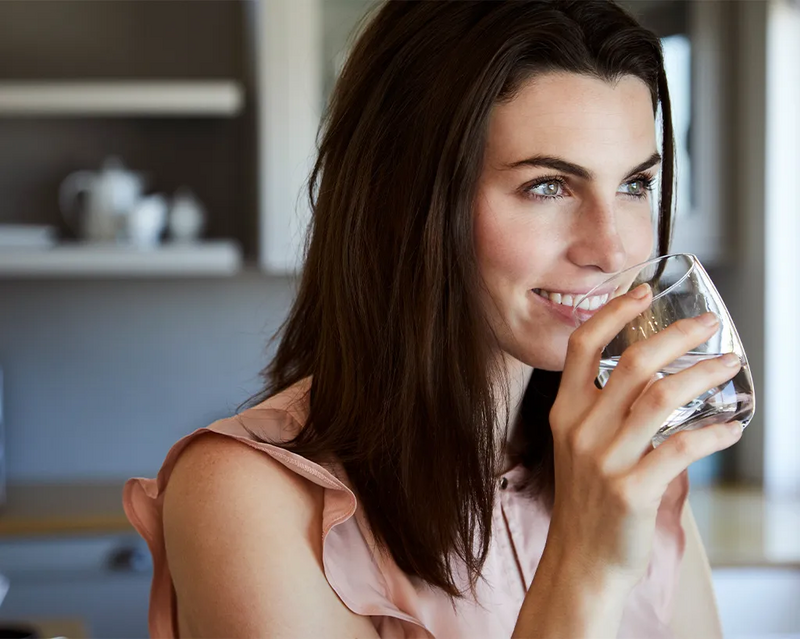 Frau trinkt Wasser aus einem Glas
