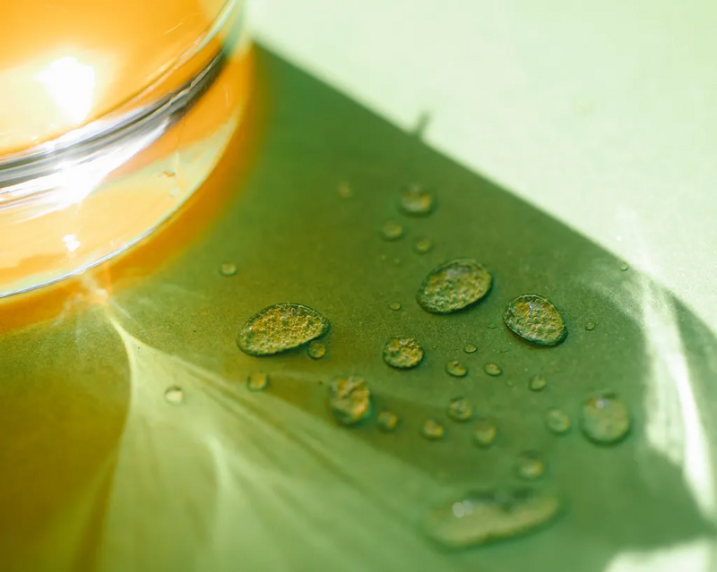 Wassertropfen auf einem Tisch neben einem Glas mit Orangensaft