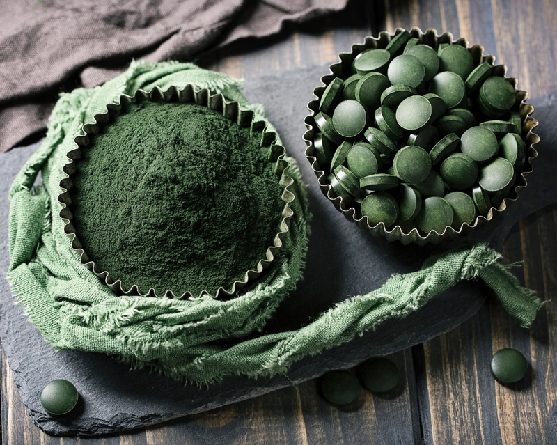 Zwei Förmchen enthalten jeweils Chlorella-Tabletten und Chlorella-Pulver