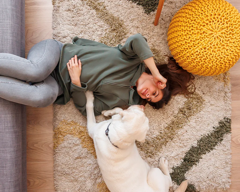 Frau entspannt auf dem Boden, neben ihr liegt ein Hund